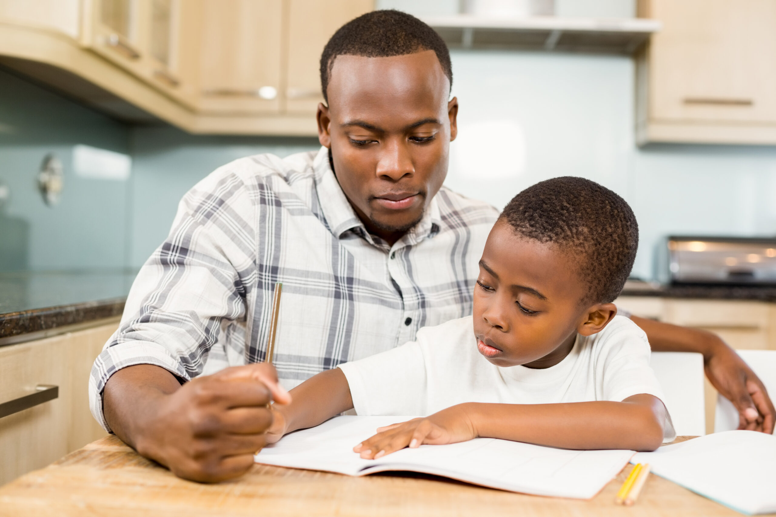 Adult helping young boy with homework in kitchen