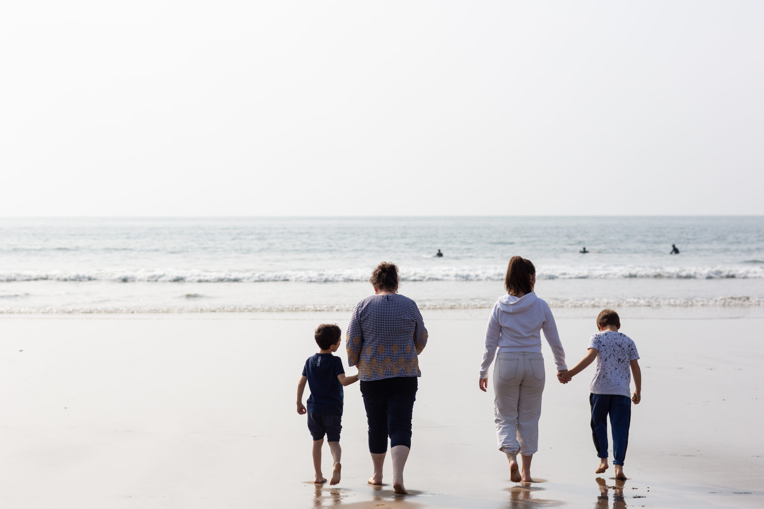 Two females walking on a beach with two children