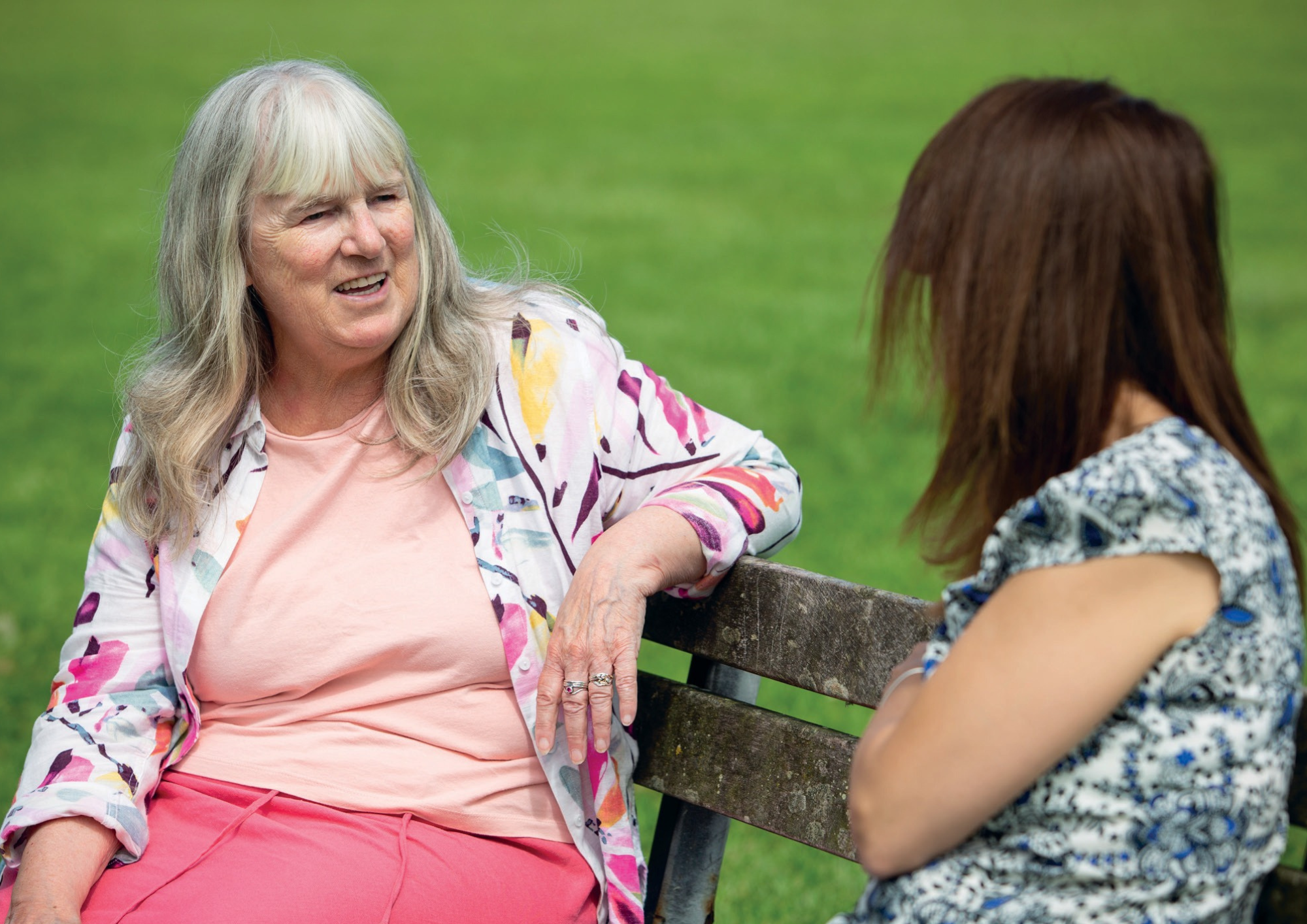 Foster carer chatting with social worker on park bench